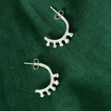 Silver Ivy bud half hoop earrings flat lay on green cloth