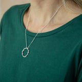 silver wreath pendant modelled around neck on green t-shirt