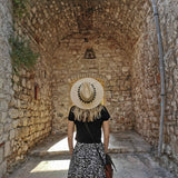 back of woman wearing hat and looking at an old brick building