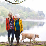 mother and daughter laughing near lake with dog