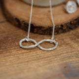 Infinity shape necklace resting on wooden background