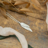 silver two leaf pendant on wood background