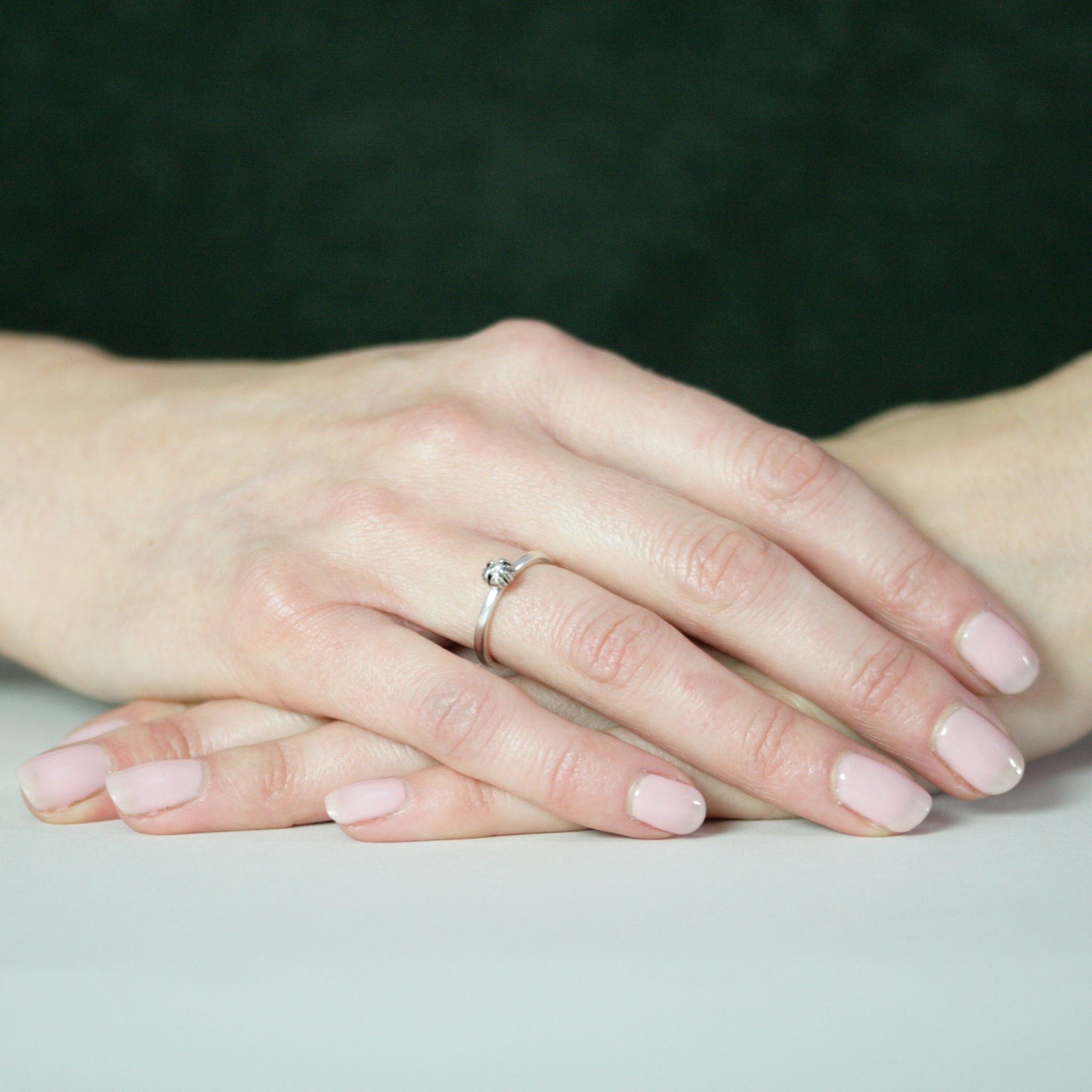 hands resting with silver bud diamond ring on finger