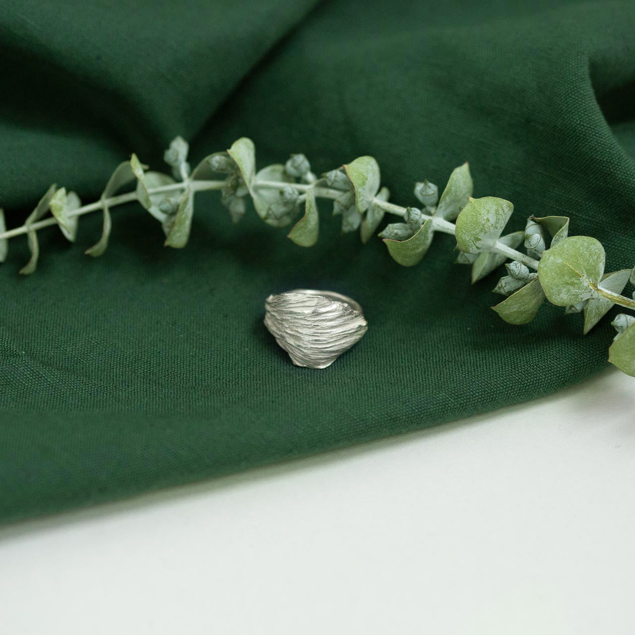 silver artichoke leaf ring on green cloth with dried flower