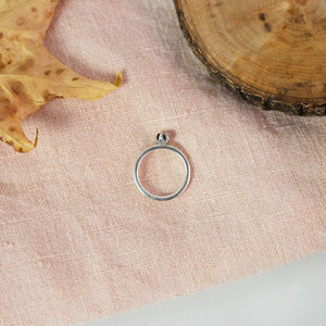 silver bud diamond ring on pink cloth near leaf and wood ring