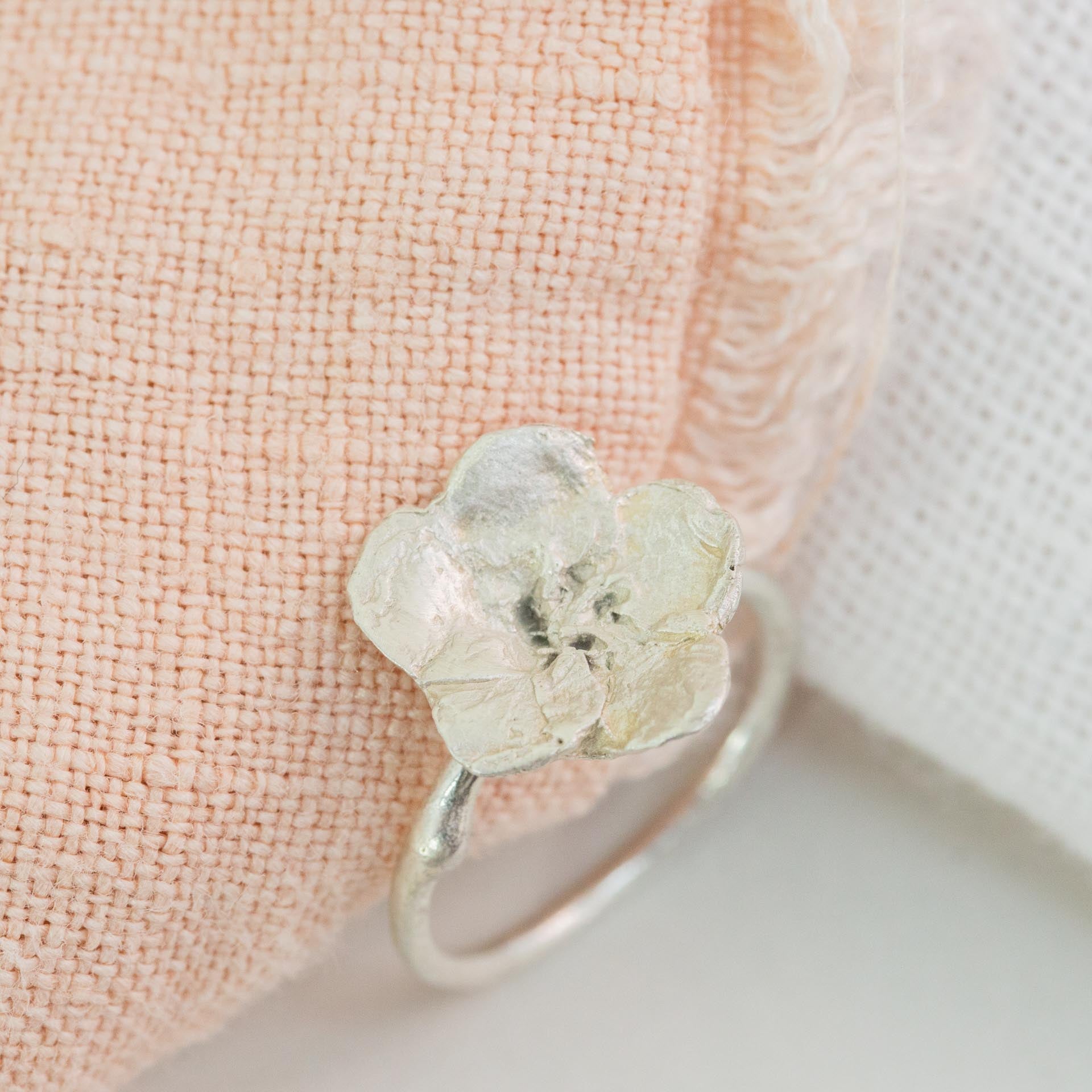 silver flower ring next to pink and white cloth