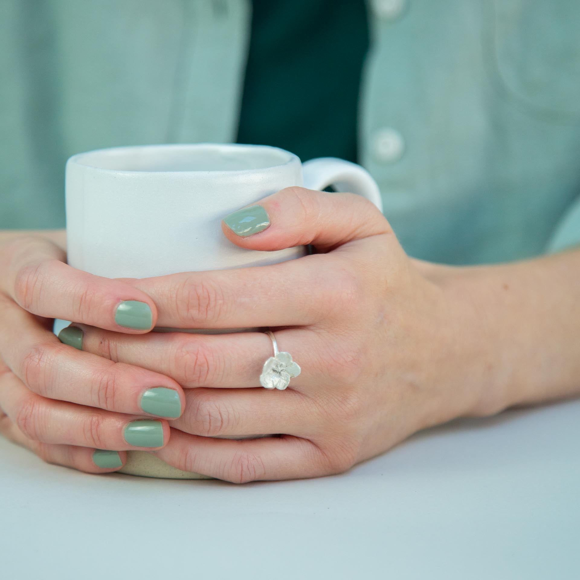 hands holding mug with silver flower ring