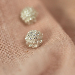silver buttercup stud earrings on pink cloth