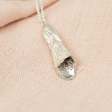 silver foxglove pendant necklace on pink cloth