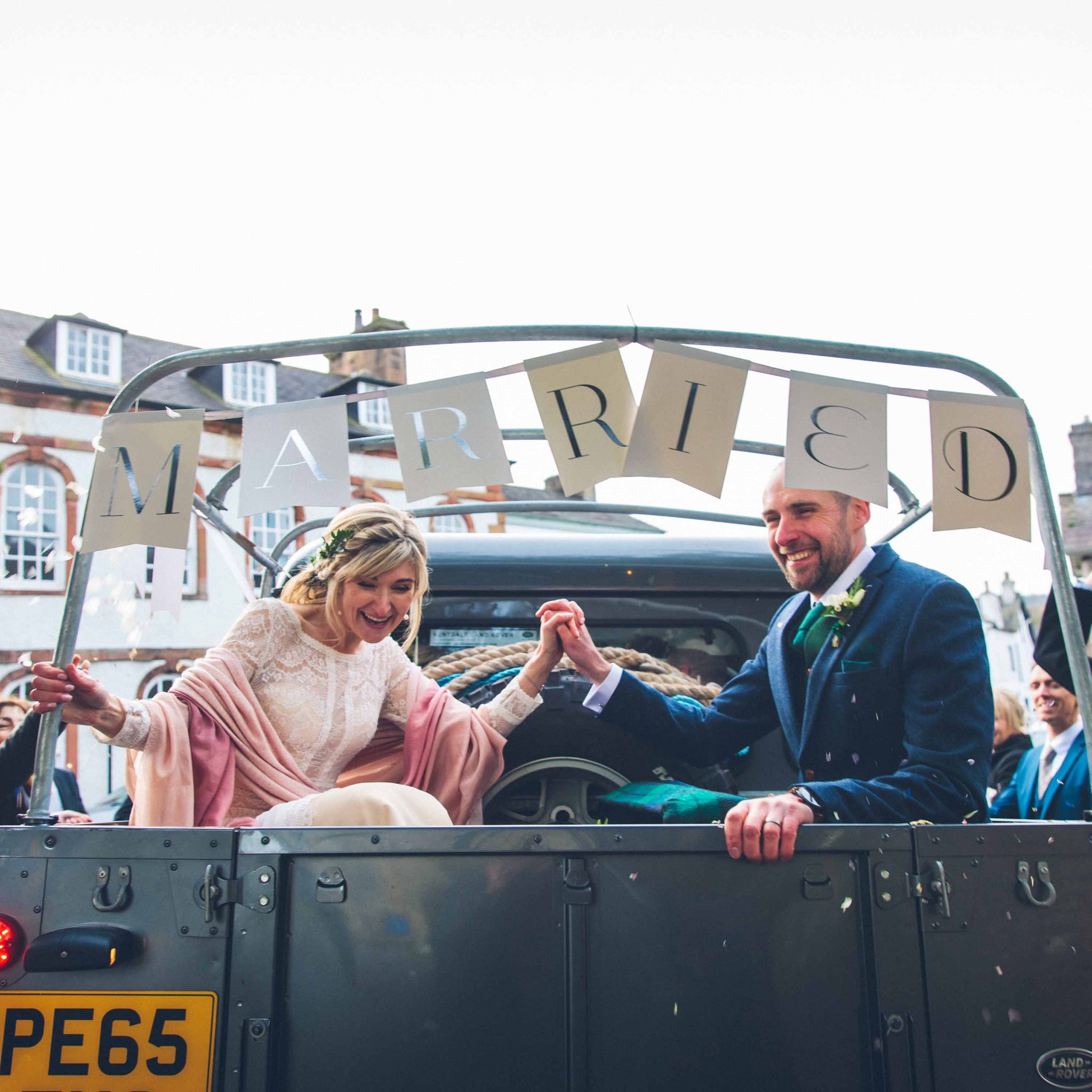 husband and wife in landrover trailer with married lettering above them