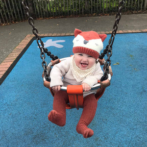 child wearing hat smiling in swing