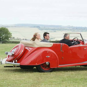 red wedding car with passangers in field