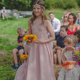 bridesmaids wearing pink dresses in outdoor wedding carrying rings on a sunflower