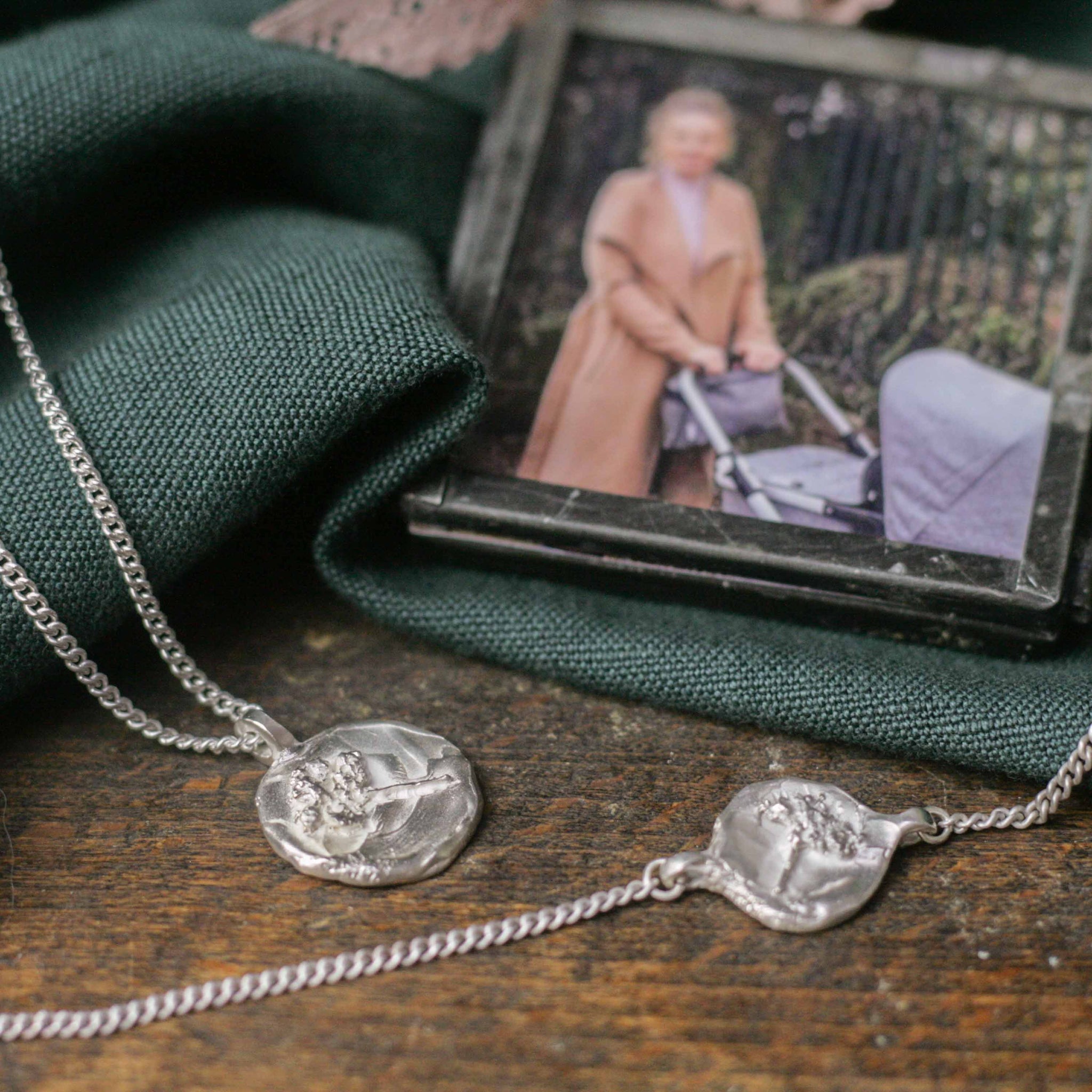 two silver relic necklaces next to photograph
