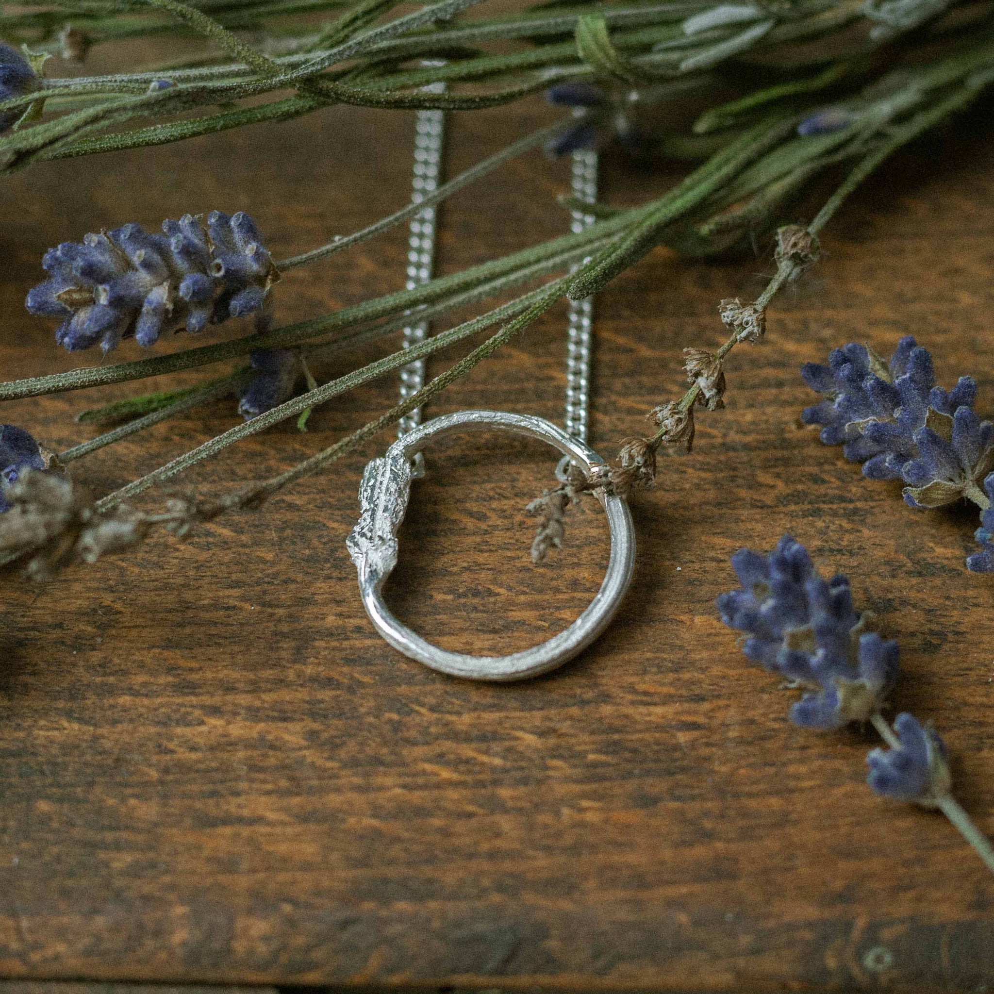 single eternity pendant on wood surrounded by dried flowers